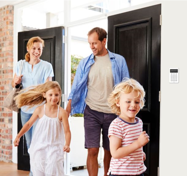 Famille qui entre à la maison avec centrale de sécurité sur la porte